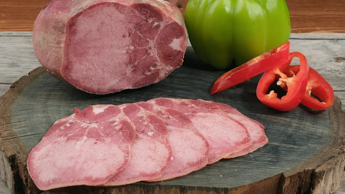 A dog looking up at sliced ham left on a kitchen counter