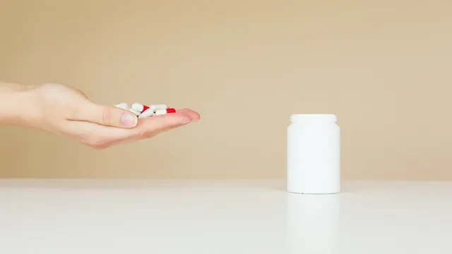 A dog owner comparing a supplement bottle and a dog treat pouch on a kitchen counter