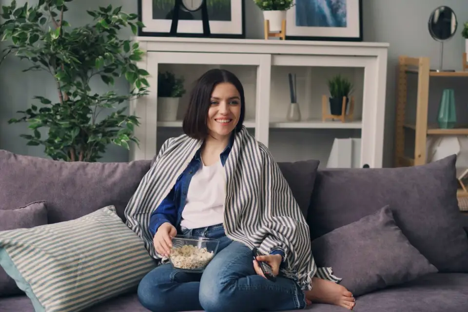 A dog sitting near a bowl of plain popcorn on a living room couch