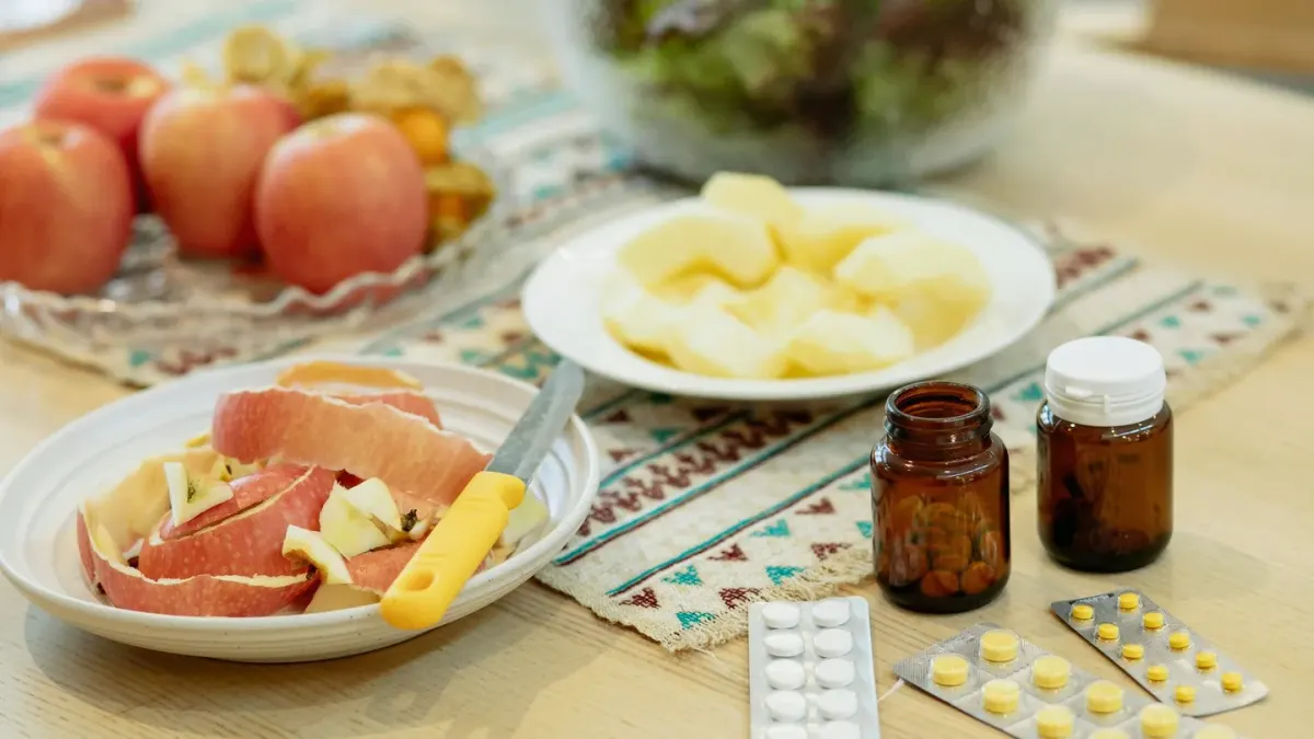 A probiotic supplement bottle standing next to a dog's stainless steel food bowl on a kitchen counter