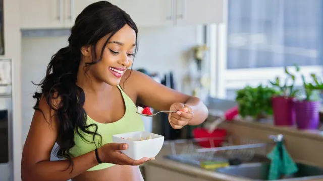 A senior dog eating from a stainless steel bowl in a sunlit kitchen