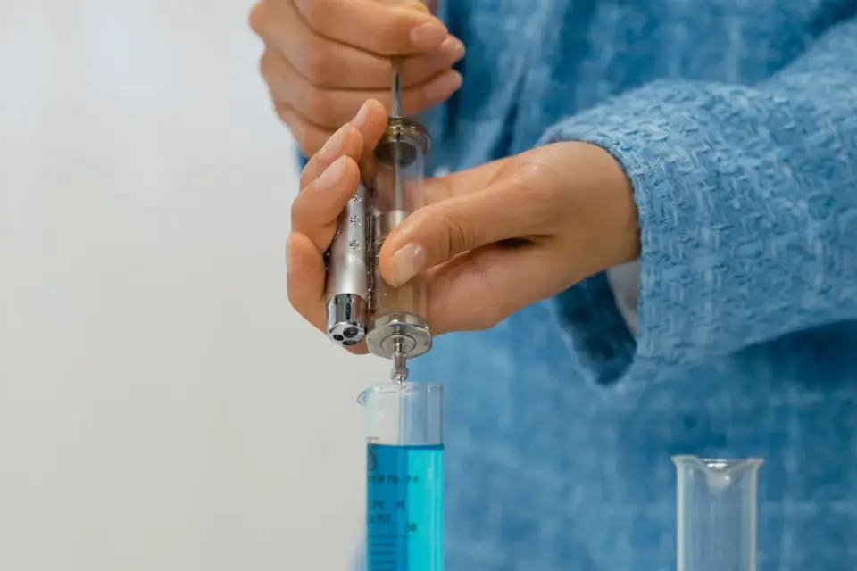 A veterinarian drawing liquid supplement into an oral syringe for a small dog