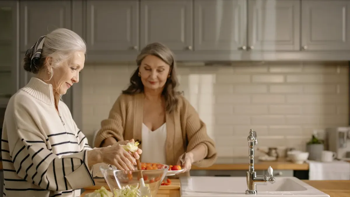 An owner holding two dog supplement packages side by side at a kitchen counter while a senior dog waits nearby