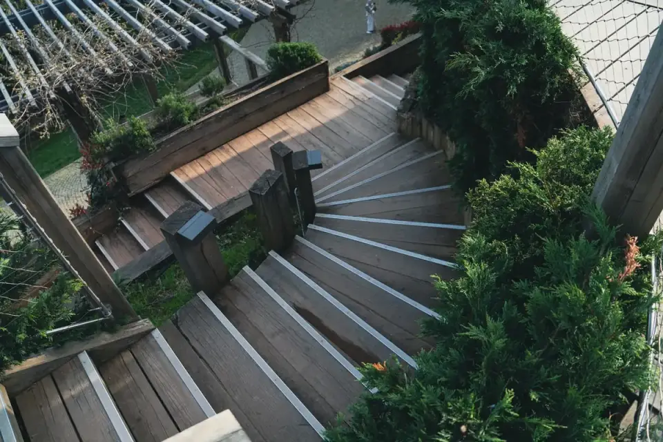 Golden retriever climbing wooden deck stairs outdoors